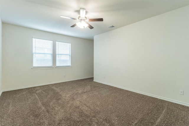 unfurnished room featuring visible vents, dark carpet, ceiling fan, and baseboards