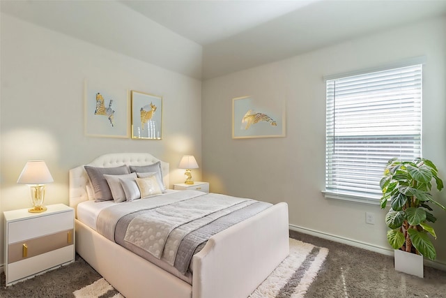 bedroom with dark colored carpet and baseboards