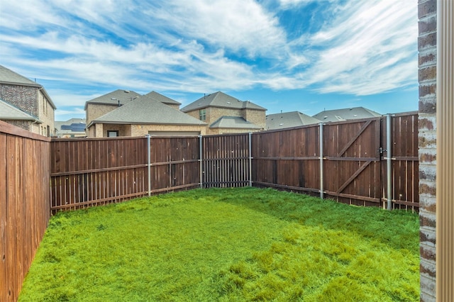 view of yard with a fenced backyard, a residential view, and a gate