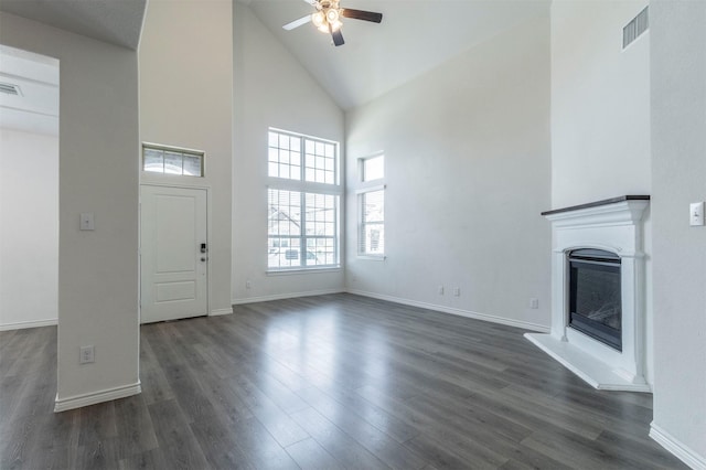 unfurnished living room featuring dark wood-style flooring, a glass covered fireplace, visible vents, and a ceiling fan