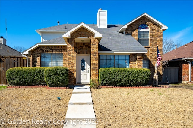 view of front of house featuring a shingled roof, a chimney, fence, a front yard, and brick siding