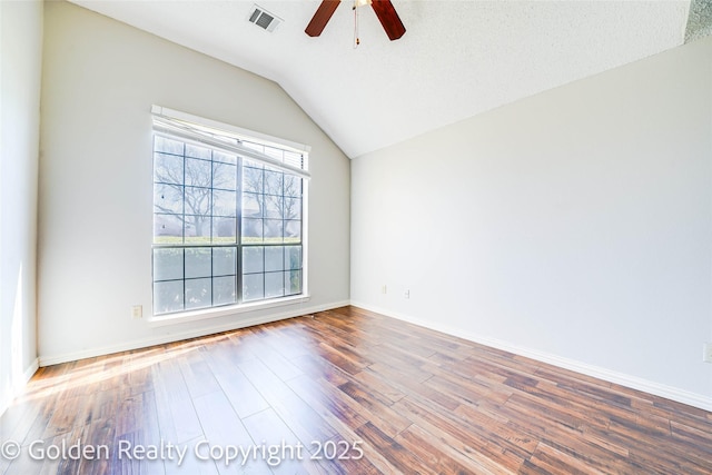 unfurnished room with baseboards, visible vents, a ceiling fan, wood finished floors, and vaulted ceiling