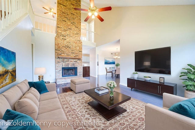 living room with a fireplace, light wood finished floors, and ceiling fan with notable chandelier