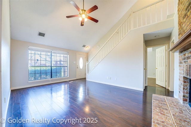 unfurnished living room with visible vents, dark wood-type flooring, a ceiling fan, a brick fireplace, and baseboards