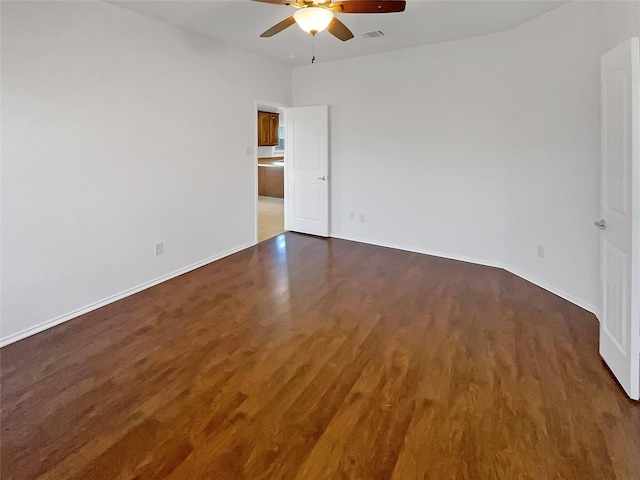 empty room with baseboards, wood finished floors, visible vents, and a ceiling fan