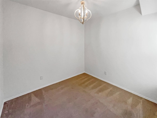 carpeted empty room with a chandelier and baseboards