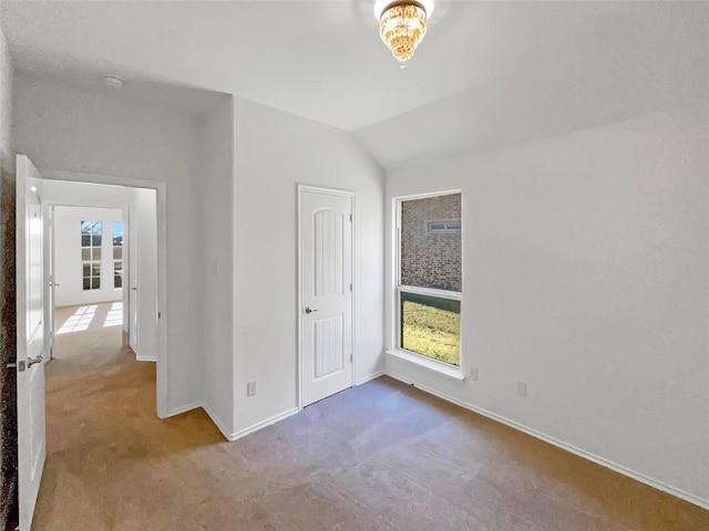 unfurnished bedroom with lofted ceiling, baseboards, multiple windows, and carpet floors