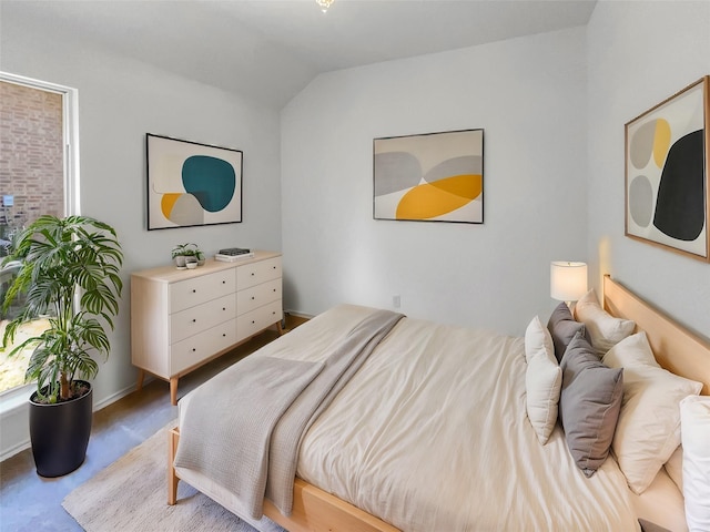 bedroom with lofted ceiling and baseboards