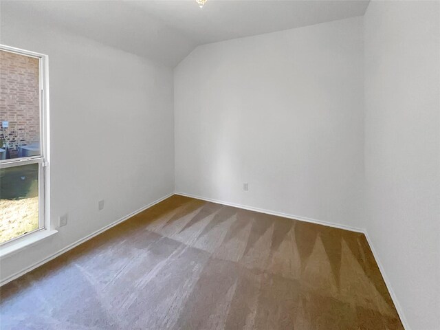 carpeted spare room with vaulted ceiling and baseboards