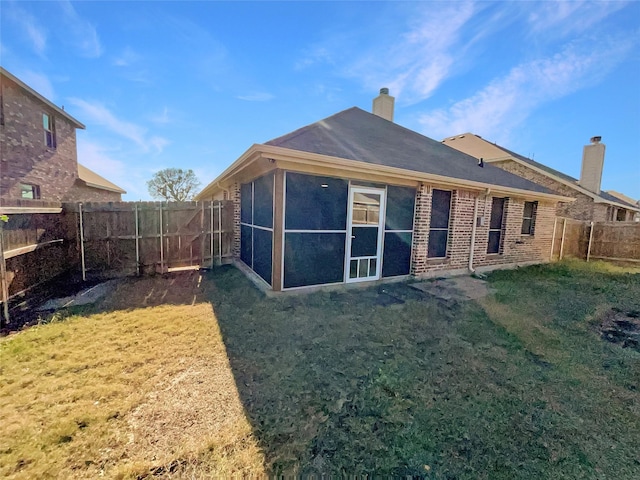 rear view of house featuring brick siding, a chimney, a fenced backyard, and a lawn