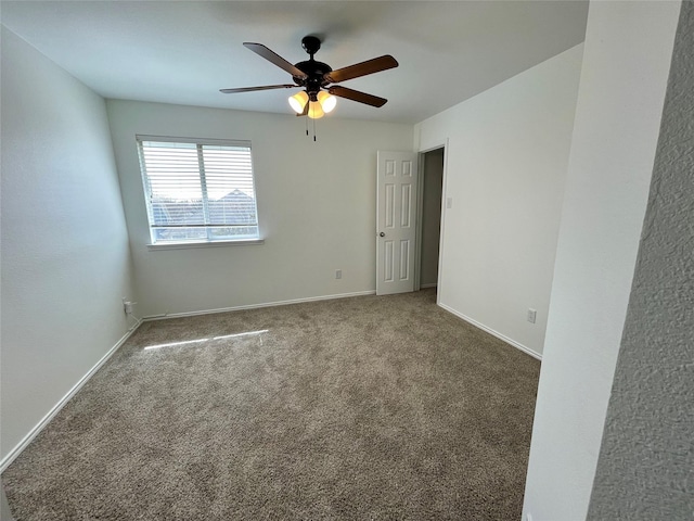 carpeted empty room with a ceiling fan and baseboards