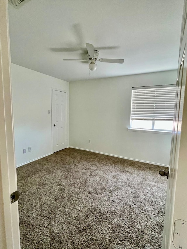 carpeted empty room with baseboards and a ceiling fan