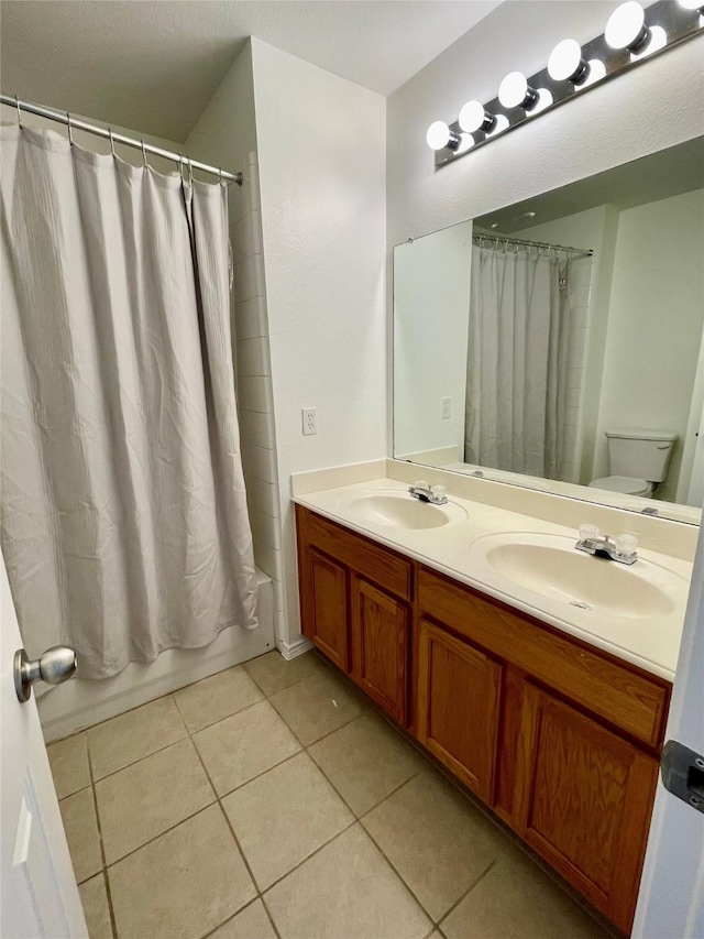 bathroom featuring double vanity, shower / tub combo, a sink, and tile patterned floors