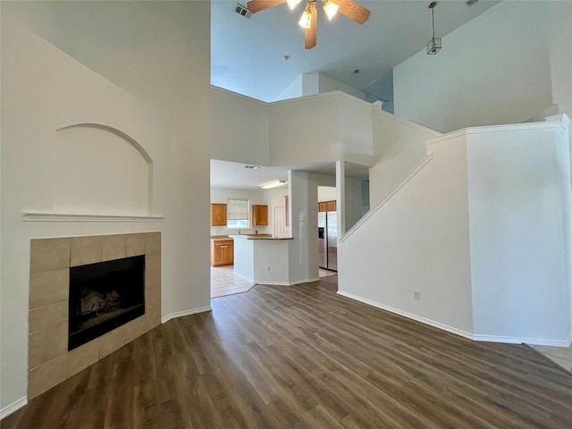 unfurnished living room with dark wood finished floors, a fireplace, visible vents, ceiling fan, and baseboards