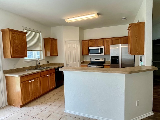 kitchen with light tile patterned floors, stainless steel appliances, visible vents, brown cabinetry, and a sink