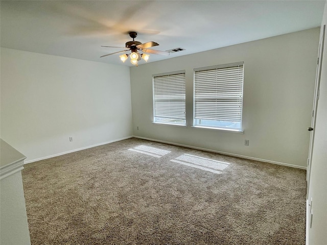 carpeted spare room featuring baseboards, visible vents, and a ceiling fan