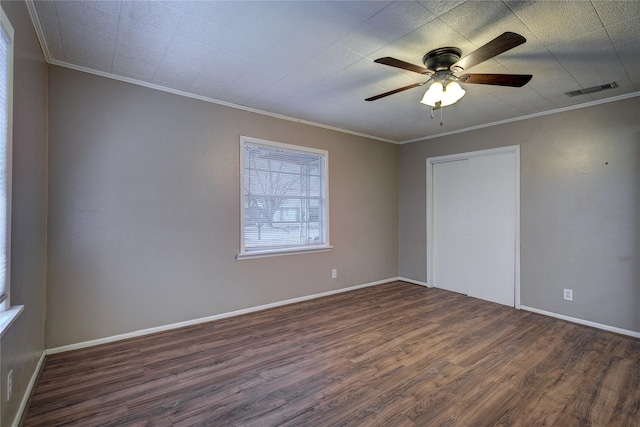 unfurnished bedroom featuring baseboards, visible vents, dark wood finished floors, and crown molding