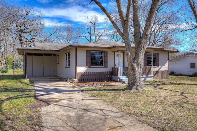 view of front of property featuring an attached carport, a front lawn, concrete driveway, and roof with shingles