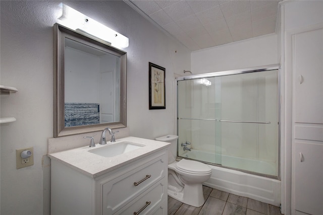 bathroom featuring toilet, enclosed tub / shower combo, wood finished floors, and vanity