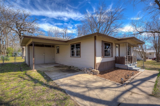 ranch-style house featuring concrete driveway, an attached carport, and fence