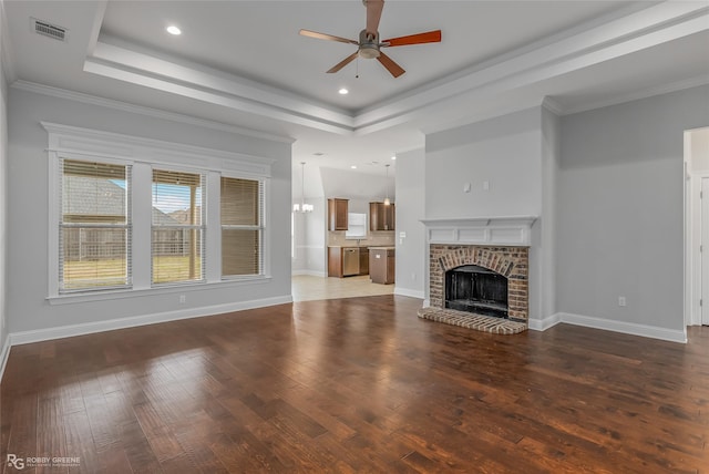 unfurnished living room with dark wood-style floors, a brick fireplace, a raised ceiling, and visible vents