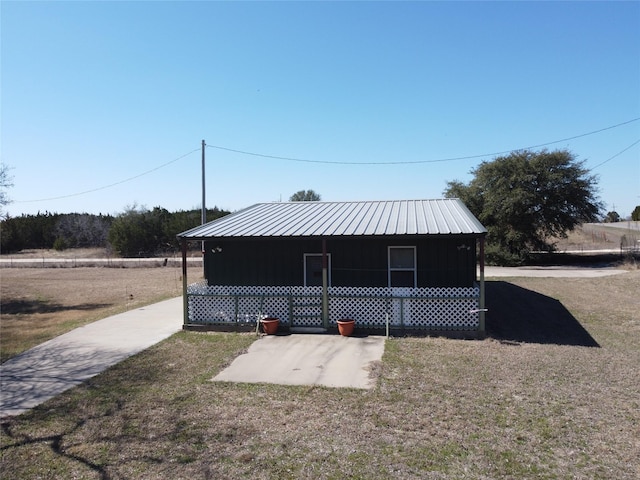 exterior space with metal roof and a front lawn