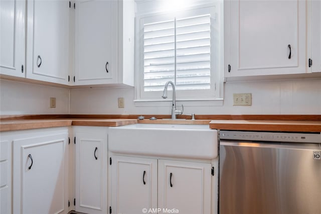 kitchen with light countertops, stainless steel dishwasher, a sink, and white cabinetry