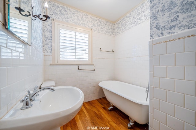 full bathroom featuring wainscoting, a sink, a freestanding bath, and wallpapered walls