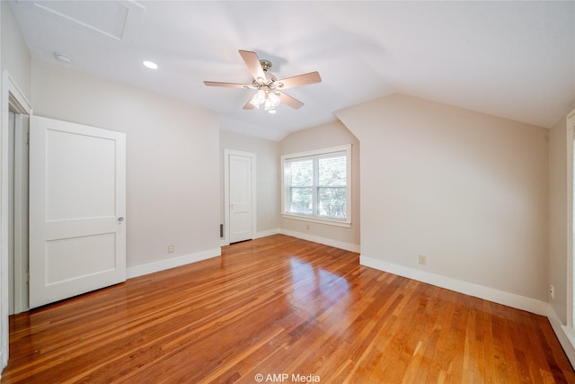 additional living space with lofted ceiling, wood finished floors, a ceiling fan, baseboards, and attic access