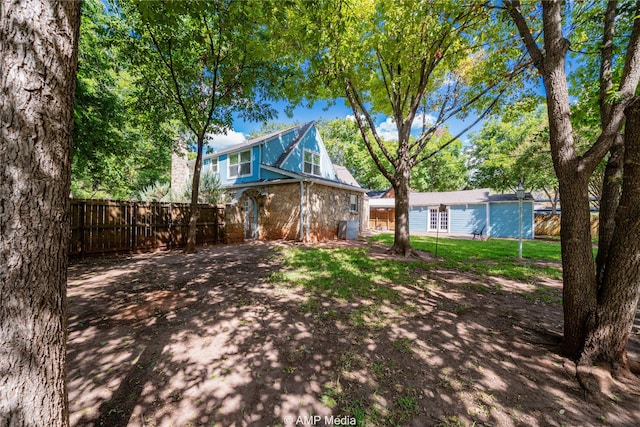 rear view of house with stone siding and fence