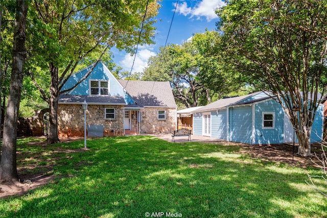 back of property with stone siding, a patio area, fence, and a yard