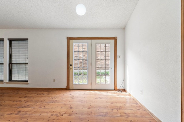 empty room with baseboards, a textured ceiling, and wood finished floors