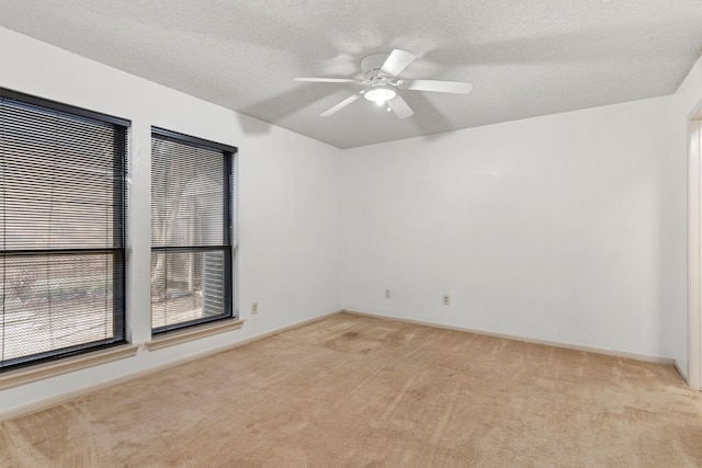 spare room featuring light carpet, baseboards, a textured ceiling, and ceiling fan