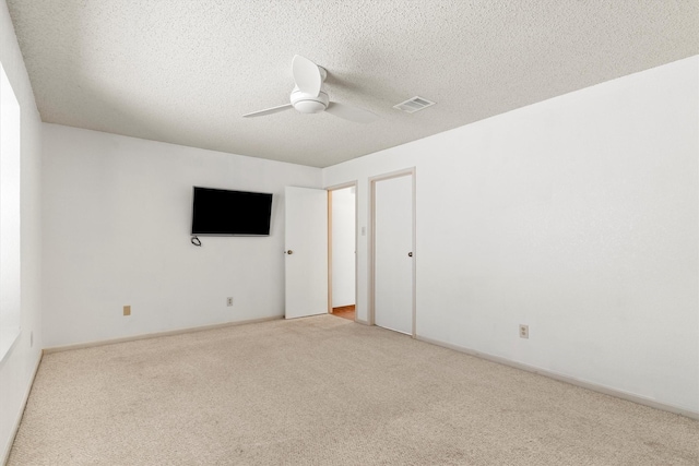 carpeted spare room featuring baseboards, a ceiling fan, visible vents, and a textured ceiling