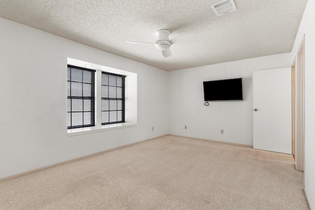 carpeted spare room featuring visible vents, a textured ceiling, and a ceiling fan