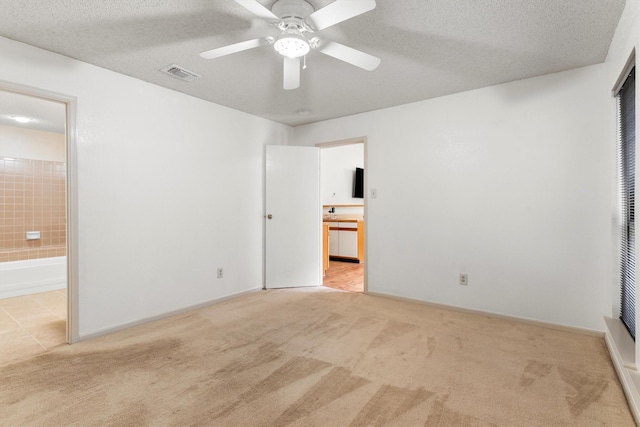 unfurnished bedroom featuring light carpet, visible vents, connected bathroom, and a textured ceiling