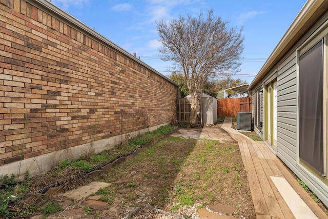 view of yard featuring a storage shed, an outdoor structure, central air condition unit, and fence