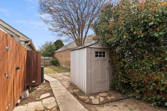 view of shed featuring central air condition unit and fence