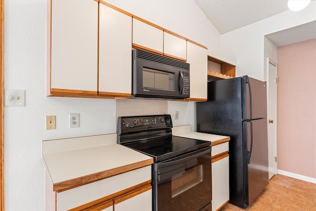 kitchen with black appliances, white cabinets, light countertops, light tile patterned floors, and vaulted ceiling