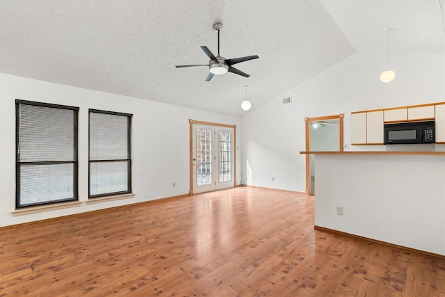 unfurnished living room featuring light wood-style flooring, a textured ceiling, ceiling fan, and vaulted ceiling