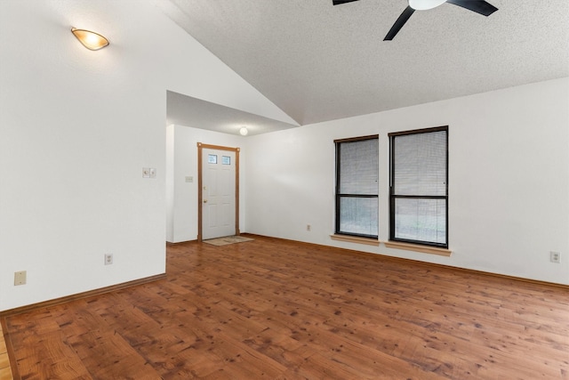 unfurnished room featuring a textured ceiling, hardwood / wood-style floors, baseboards, ceiling fan, and vaulted ceiling