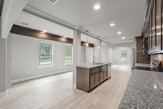 kitchen with arched walkways, stainless steel appliances, visible vents, dark stone countertops, and pendant lighting