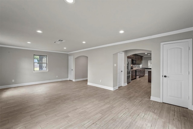 empty room with light wood finished floors, baseboards, arched walkways, and recessed lighting