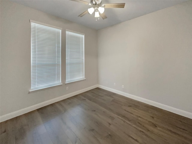 empty room featuring dark wood finished floors, a ceiling fan, and baseboards