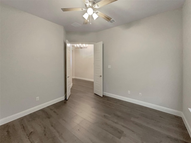 unfurnished room with visible vents, dark wood finished floors, baseboards, and ceiling fan with notable chandelier