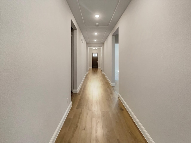 hallway featuring light wood-style flooring and baseboards