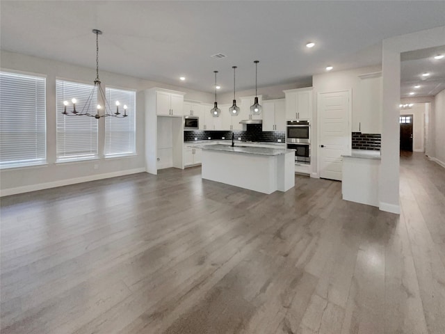 kitchen featuring appliances with stainless steel finishes, wood finished floors, white cabinets, and decorative backsplash