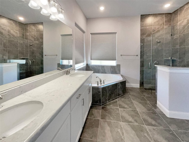 bathroom featuring a bath, a shower stall, double vanity, and a sink