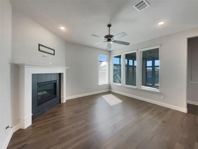 unfurnished living room with baseboards, visible vents, dark wood-type flooring, and a tile fireplace