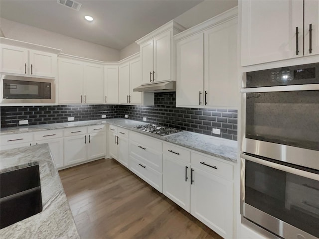 kitchen with under cabinet range hood, visible vents, stainless steel appliances, and backsplash